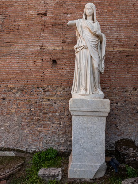 Inscribed Vestal statue against brick wall