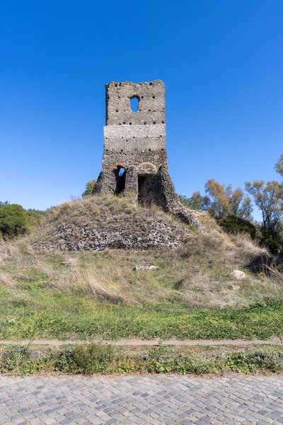 Crumbling tower above grassy mound, Via Appia