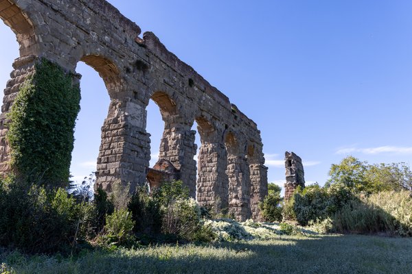 Crumbling aqueduct arches against blue sky
